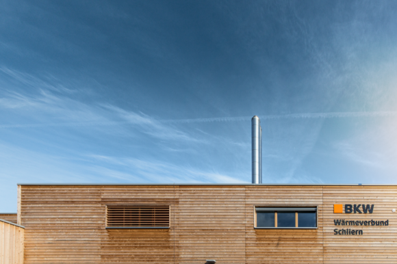 [Translate to Italienisch (CH):] Das Holzhaus eines Wärmeverbunds vor blauem Himmel