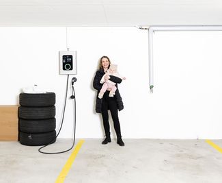 Femme avec bébé dans ses bras devant une station de charge