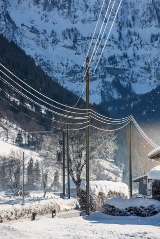 L'image montre une ligne électrique du niveau de réseau 3 en hiver. En arrière-plan, on peut voir une paroi rocheuse recouverte de neige.