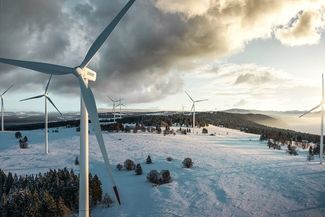 Bewölkte Schneelandschaft mit Windkraftwerk von Juvent