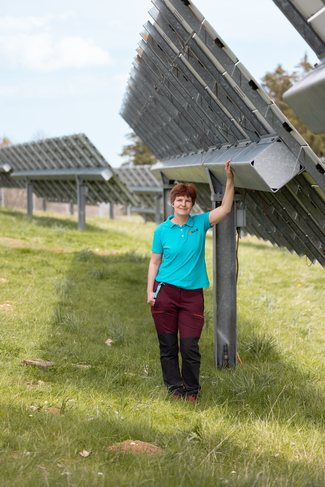 Frau steht vor grossen aufgerichteten Solarpanels