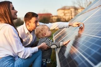 Familie mit Kleinkind betrachtet Solarpanel