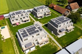 Blick auf mehrere Mehrfamilienhäuser mit Solaranlagen auf den Dächern