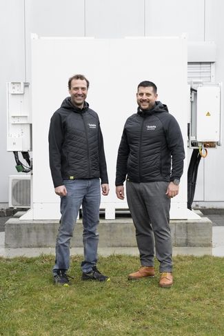 Zwei Mitarbeiter der Solstis stehen vor dem Batteriespeicher