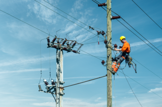 Il s'agit d'un pylône électrique de niveau 3. Un électricien de réseau en uniforme orange travaille sur le réseau électrique.