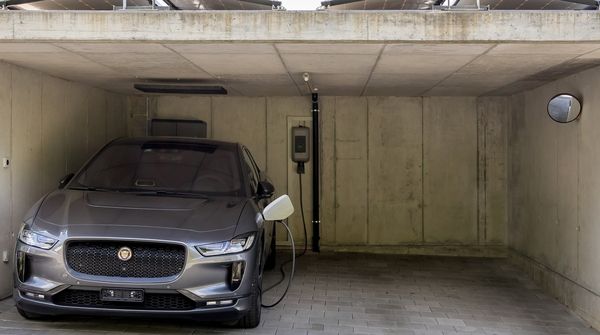 Ein silbernes Elektroauto lädt an einer Ladestation zuhause.