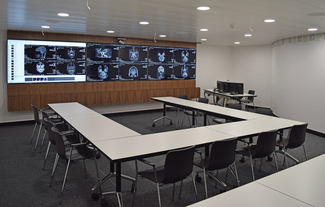 U-förmiger Konferenztisch mit Stühlen und grosser Bildschirm an Frontwand