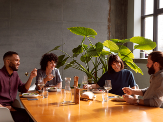 Quatre personnes assises à table et partageant un repas dans une belle salle à manger.