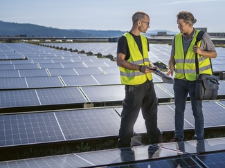 Deux hommes se tiennent sur un toit avec un panneau solaire